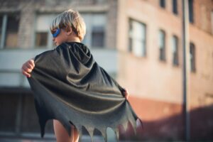 A young child wears a cape
