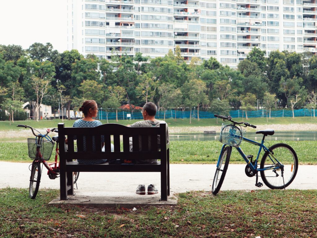 A retired couple sits on a bench near their bikes