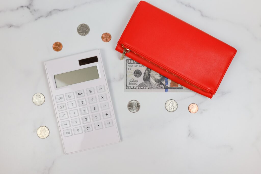 A calculator, money, and a pouch sit on a marble counter