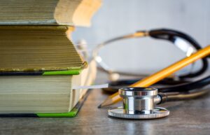 A stethoscope sits next to a stack of books